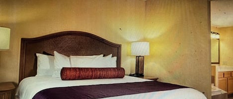 Una habitación de hotel con una cama grande, una mesita de noche y una lámpara fijada a la pared.