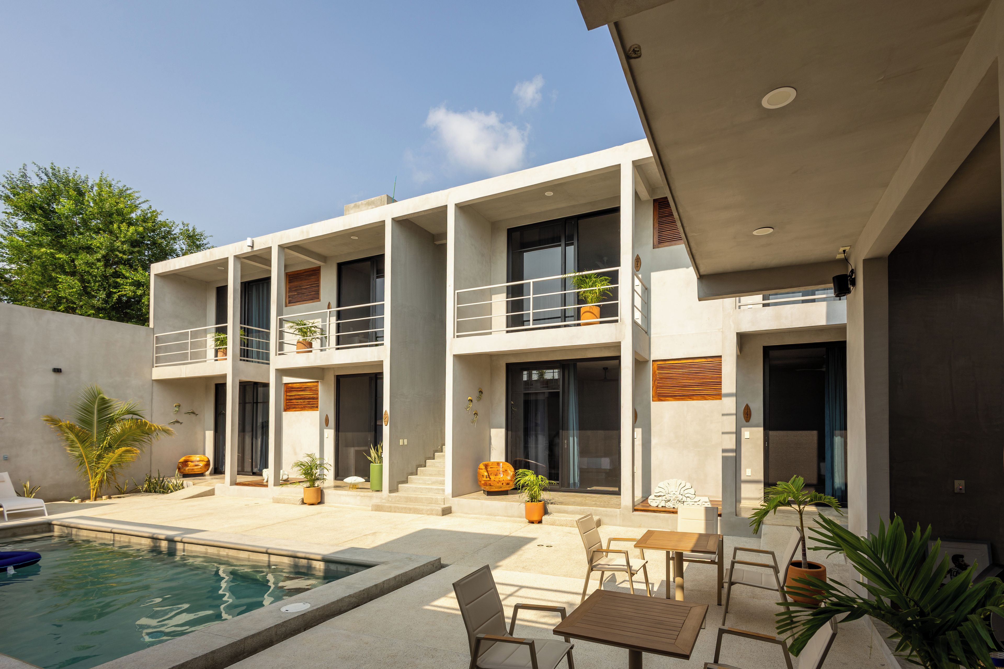 A modern two-story house with a swimming pool, outdoor seating, and multiple balconies.
