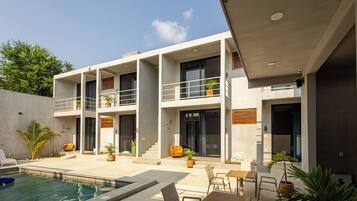 A modern two-story house with a swimming pool, outdoor seating, and multiple balconies.