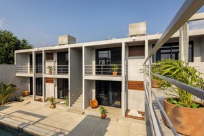 A modern multi-story building with balconies, potted plants, and a pool area. - Casa Oceana (Brisas de Zicatela)