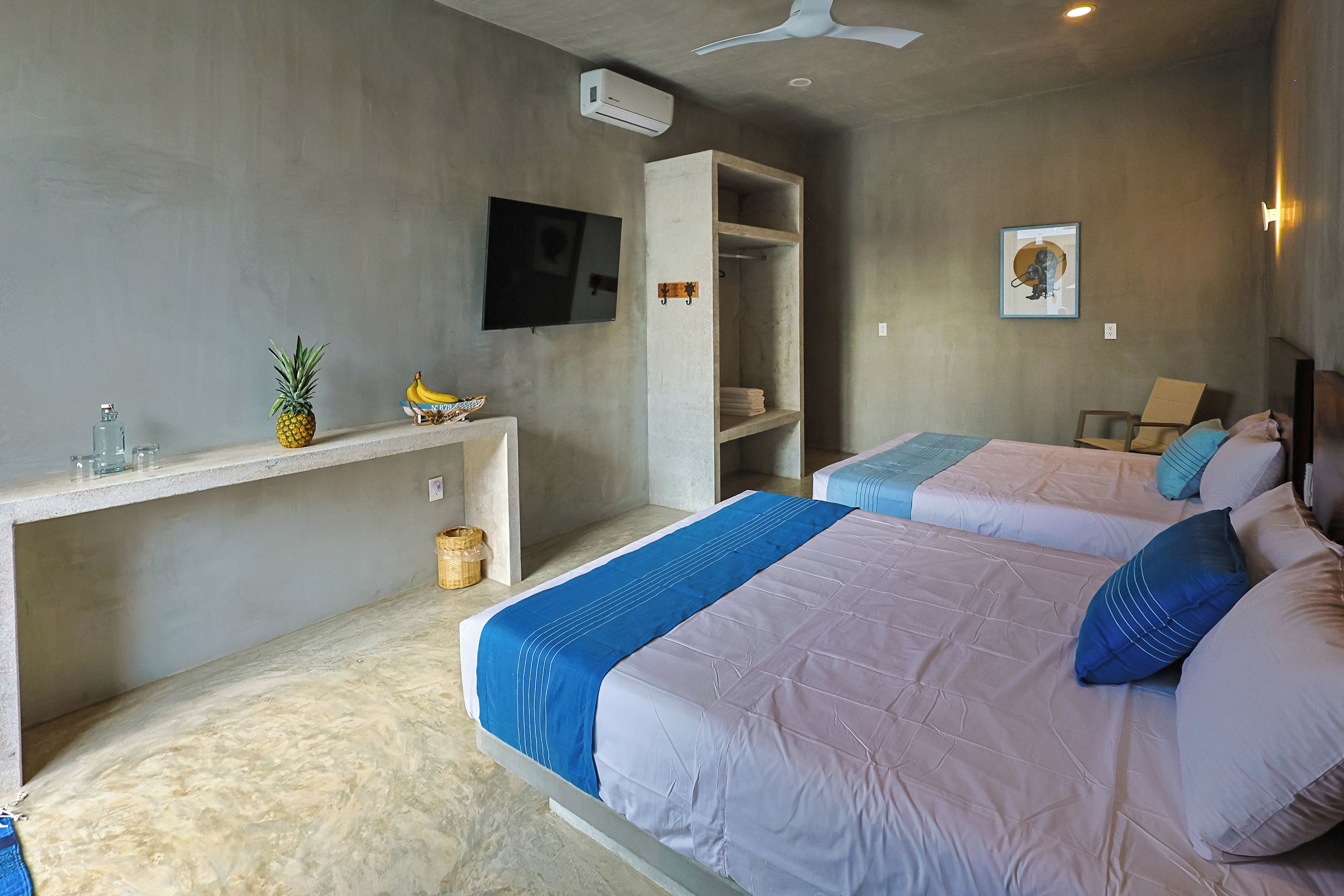 Habitación de hotel con dos camas, un escritorio, un televisor y un armario.