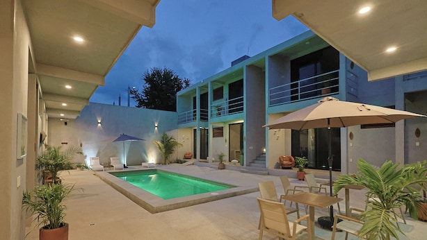 Um edifício moderno com piscina, área de estar externa e plantas em vasos.