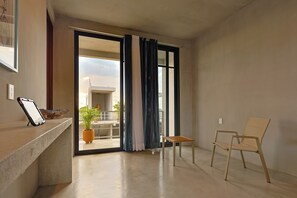 En moderne stue med en skydedør til en balkon, et lille træbord, en stol og en potteplante.