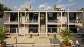 Un edificio moderno de varios pisos con balcones, ventanas amplias y plantas en macetas.