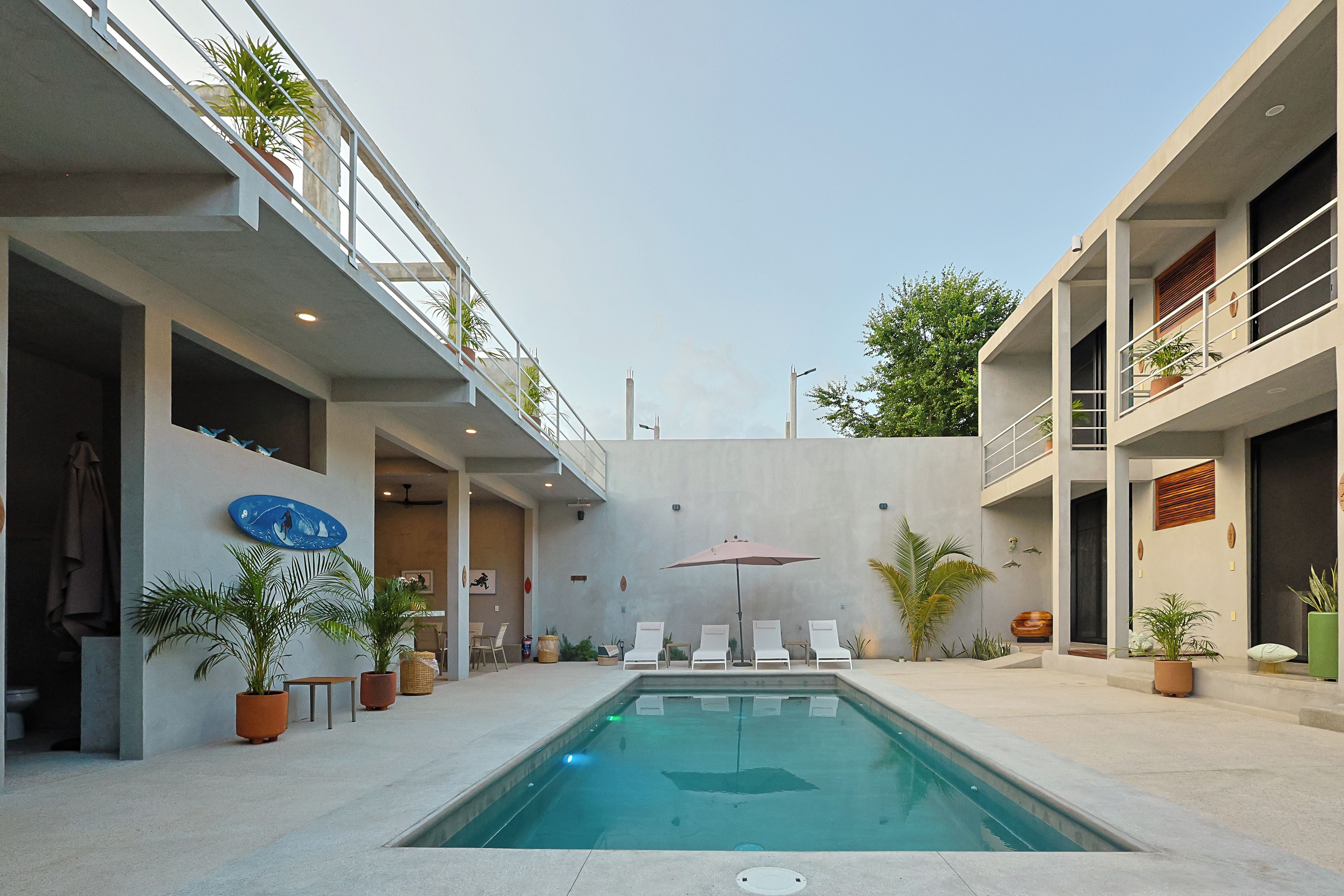 A modern pool area with a clear pool, lounge chairs, and potted plants.