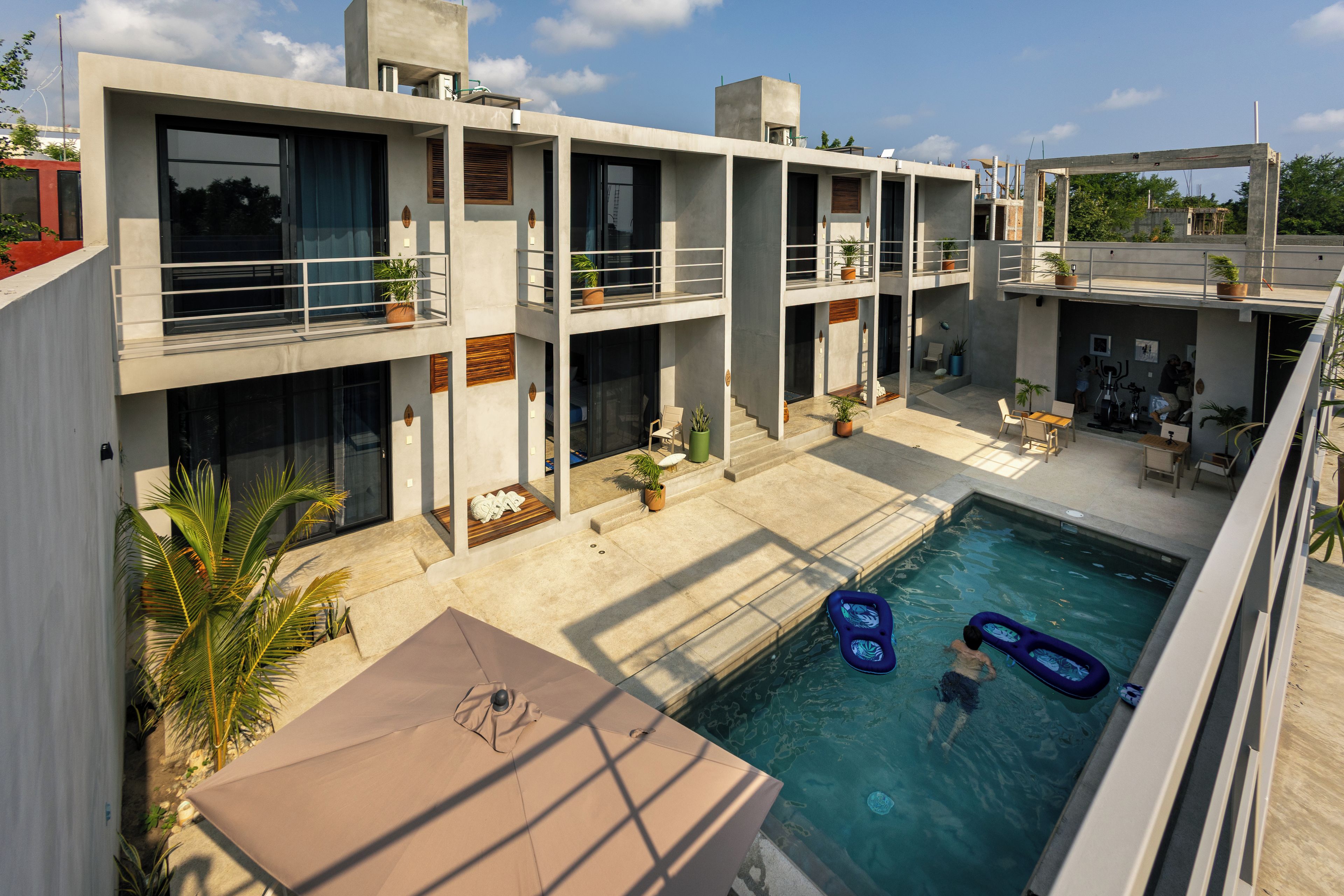 A modern building with a swimming pool, outdoor seating, and potted plants.