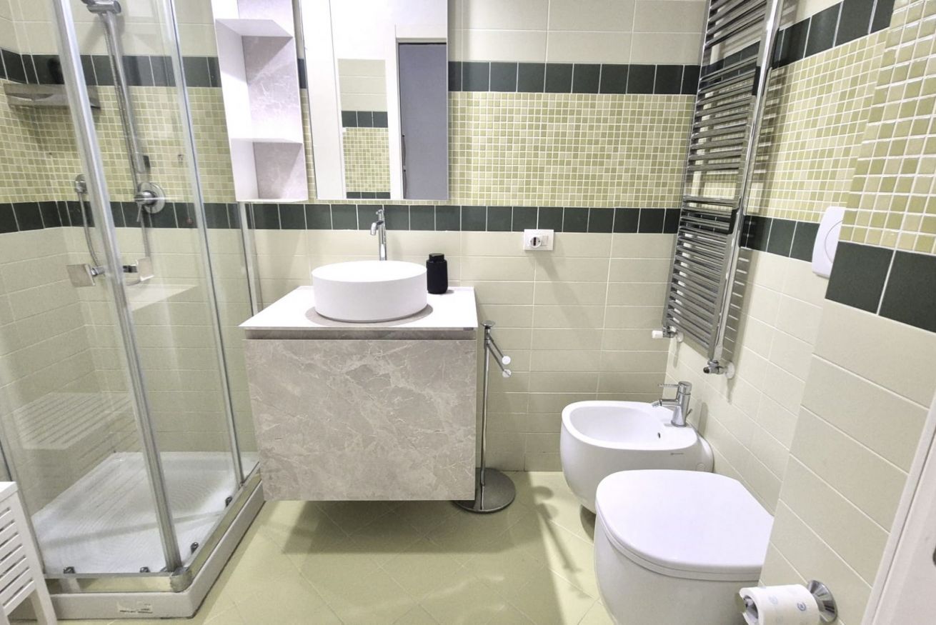 Une salle de bain avec une douche à parois de verre, un lavabo, des toilettes et un bidet.