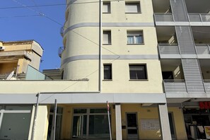Un edificio de varios pisos con balcones, un letrero visible y un cielo despejado.