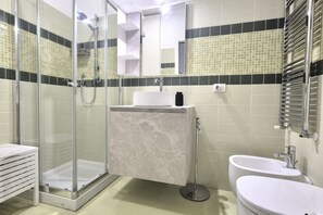 Un baño moderno con ducha envuelta en cristal, un lavabo blanco y un espejo sobre el lavabo.