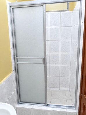 A shower enclosure with a sliding door, tiled walls, and a tiled floor. - HOTEL MILENIO (Guayaquil)