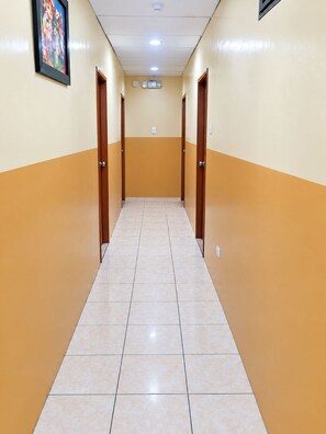 A corridor with doors on both sides, a tiled floor, and a ceiling with recessed lighting. - HOTEL MILENIO (Guayaquil)