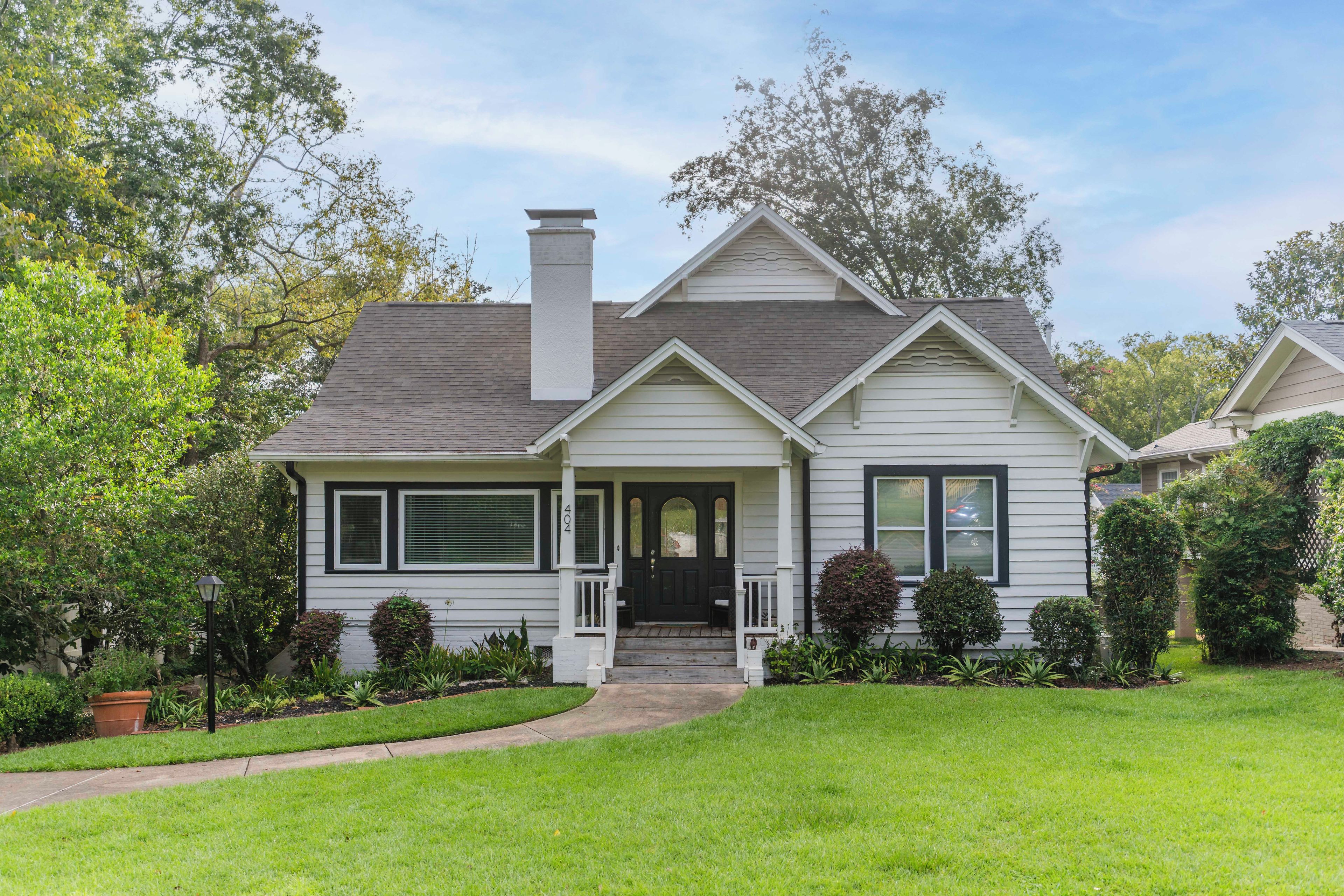 A two-story house with a front porch, a chimney, and a well-maintained lawn.