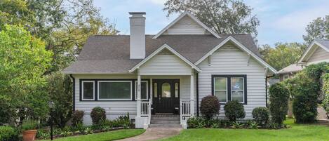 A two-story house with a front porch, a chimney, and a well-maintained lawn.