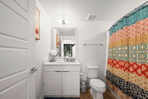 A bathroom with a white vanity, a mirror, a toilet, and a shower curtain with a geometric pattern. - U of U, Convention, Pool & Hot Tub, Gym (Salt Lake City)