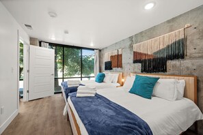 A modern bedroom with a large bed, two bedside tables, and a view through a sliding door to an outdoor area. - U of U, Convention, Pool & Hot Tub, Gym (Salt Lake City)