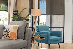 Ein modernes Wohnzimmer mit einem grauen Sofa, einem blauen Sessel und einer Stehlampe.