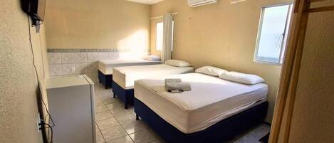 Habitación de hotel con dos camas, una kitchenette pequeña y un televisor.