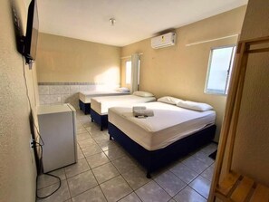 A hotel room with two beds, a small kitchenette, and a TV. - Pousada Dom Manuel (Fortaleza)