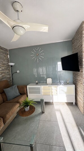 Een moderne woonkamer met een bank, salontafel en een tv aan de muur.
