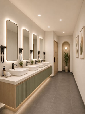 Un baño alargado y estrecho con varios lavamanos, espejos y secadores de pelo.