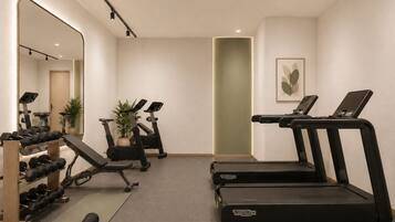 Une salle de sport équipée de tapis de course, d’haltères et d’autres appareils d’exercice.