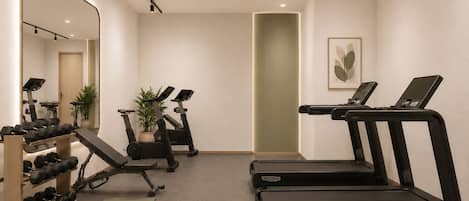Une salle de sport équipée de tapis de course, d’haltères et d’autres appareils d’exercice.