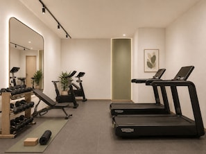 Un gimnasio con cintas de correr, pesas y equipamiento de ejercicio.
