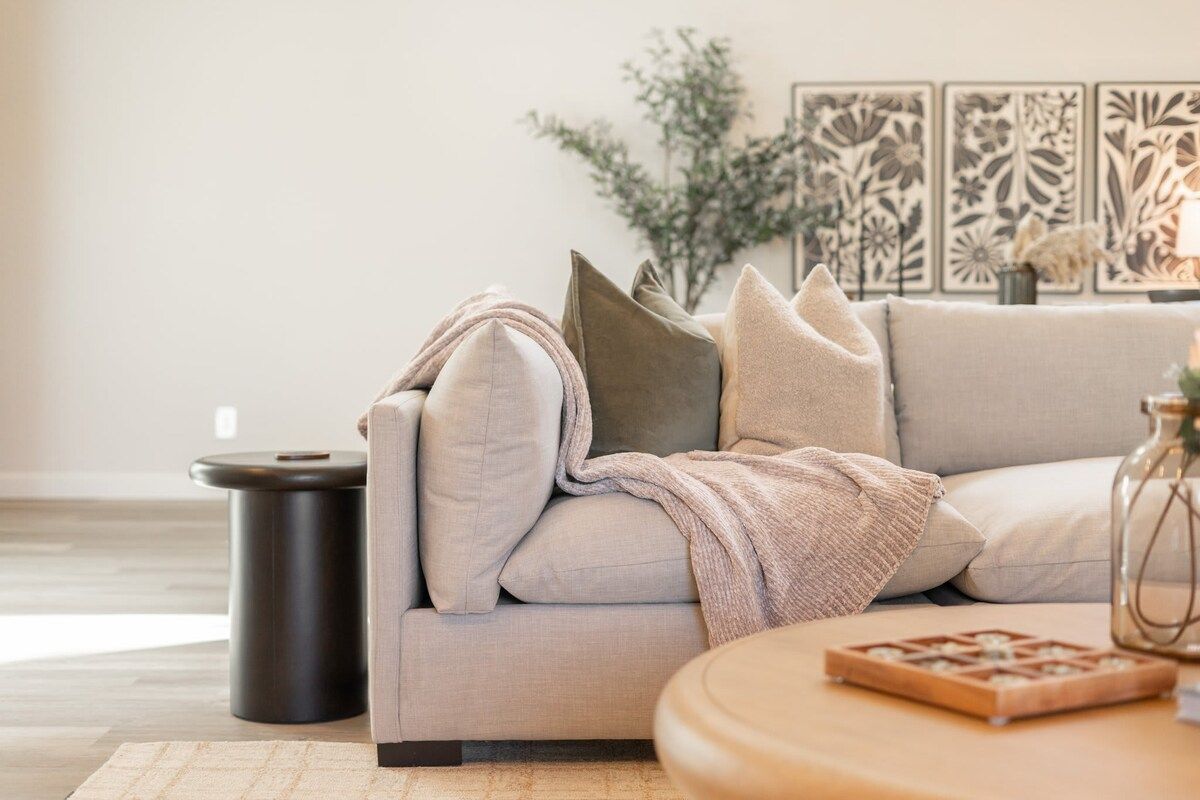 A modern living room with a sofa, a round coffee table, and decorative wall art.