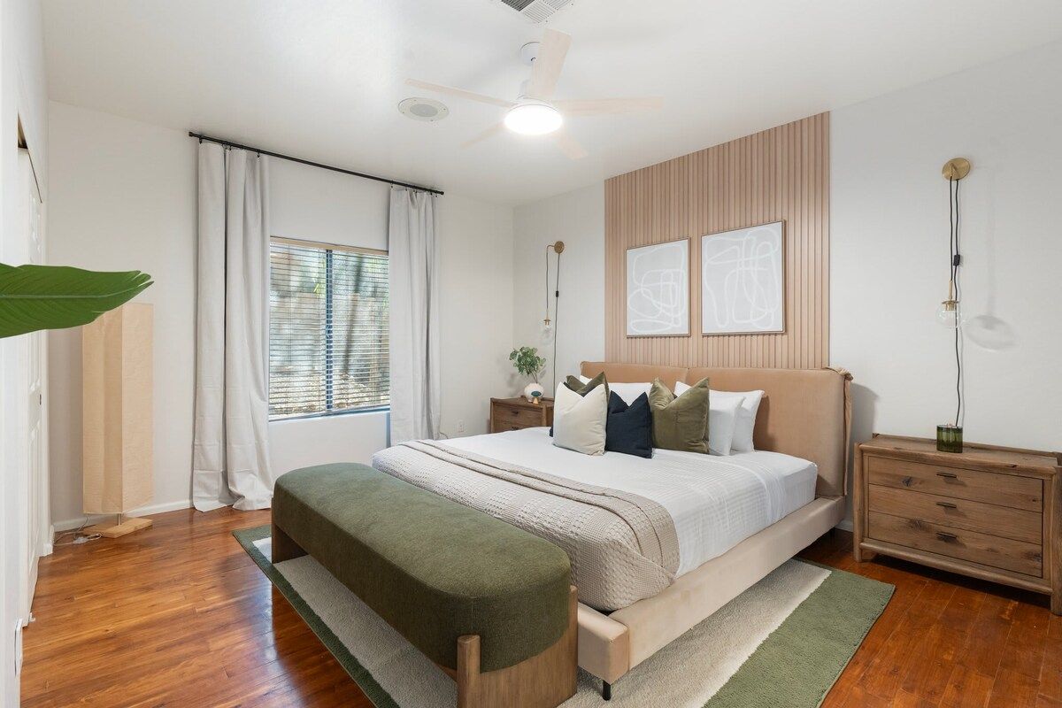 Un dormitorio con cama, una banca, una mesita de noche y un ventilador de techo.