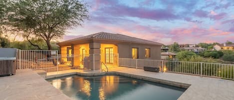 A residential property with a swimming pool, a fenced patio, and a house with a tiled roof.