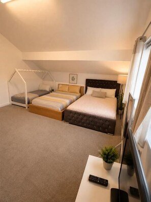A hotel room with a bed, a desk, a chair, a TV, and a window. - OYO Bethel Apartments (Leeds)