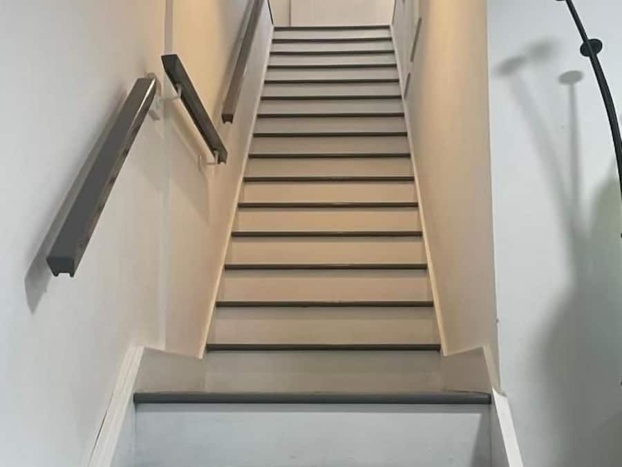 Una escalera con barandilla a la izquierda y un accesorio de iluminación en la parte superior.