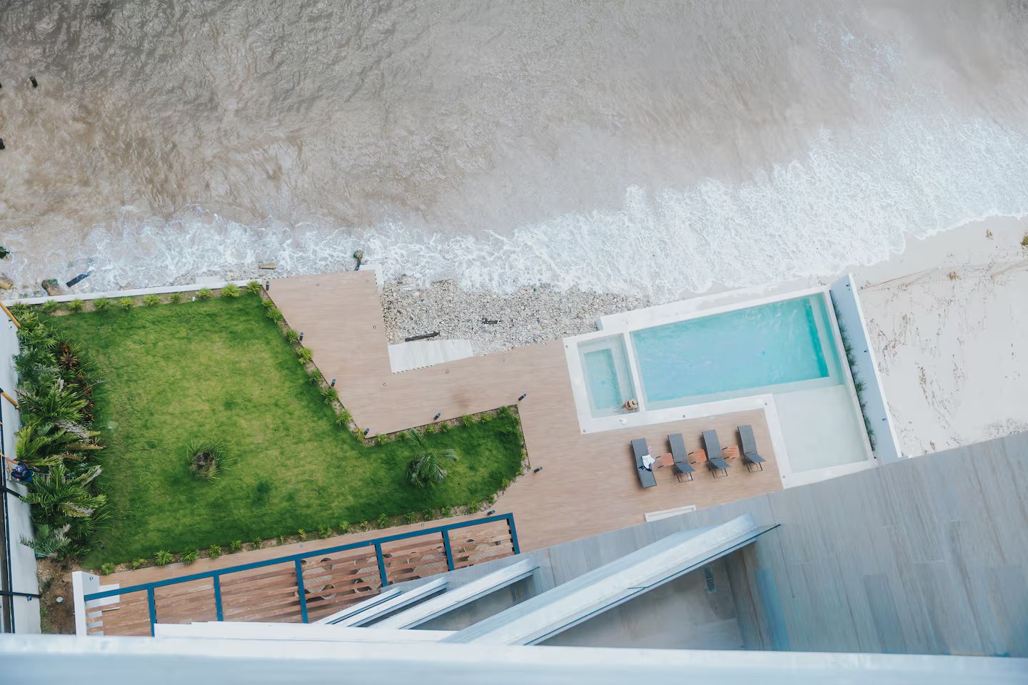 Vista aérea de um resort com piscina, área gramada e praia.