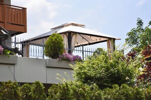A covered outdoor area with a metal railing, surrounded by greenery and flowering plants. - Terrific 2-bedroom apartment with AC in Trentino-Alto Adige (Trentino-Alto Adige)