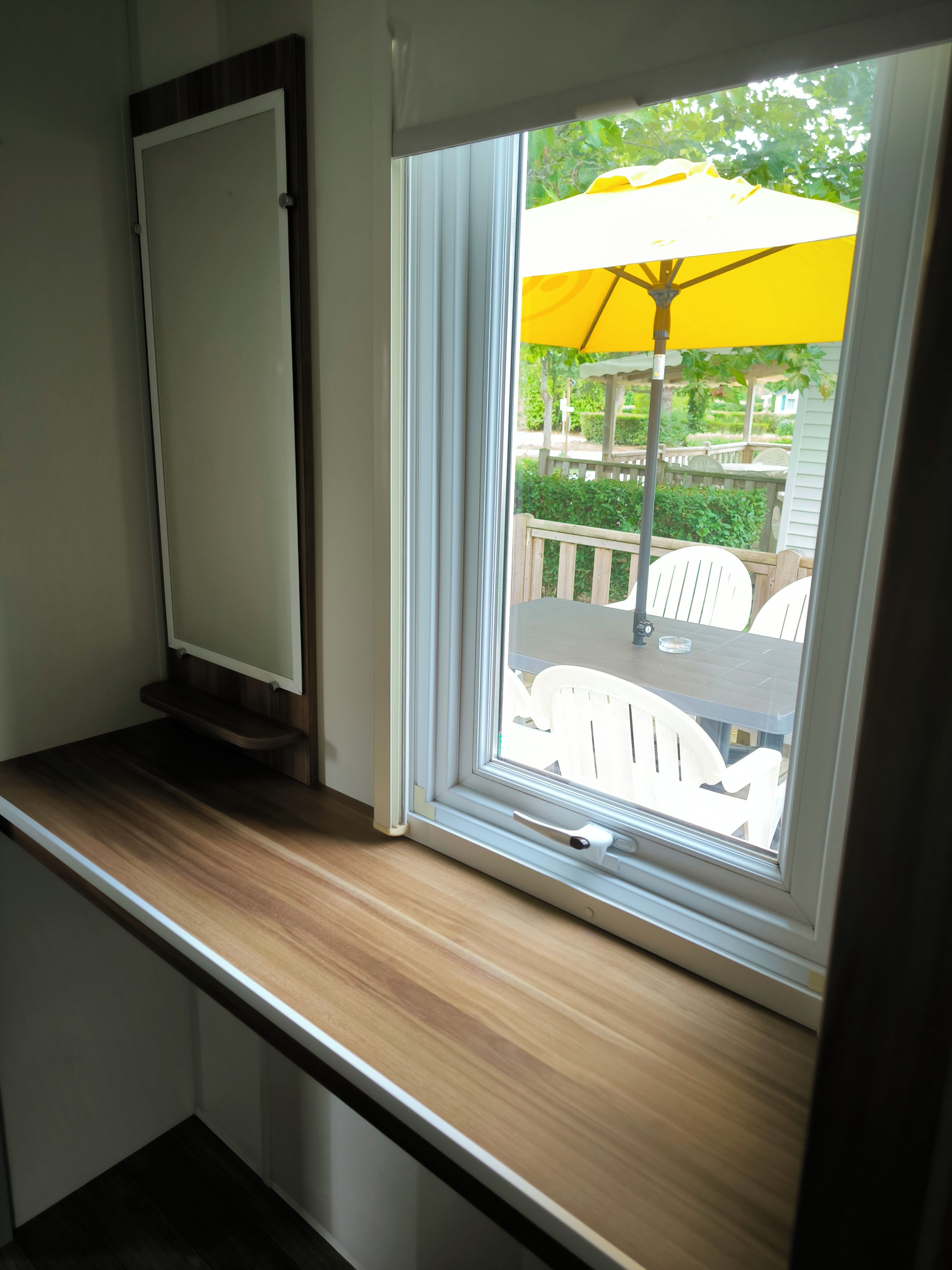 A window with a view of outdoor furniture and greenery.