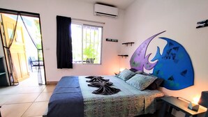Quarto com cama, janela, obra de arte na parede e porta para área externa.