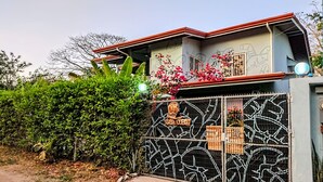 Propriedade murada com cerca de metal, um pequeno jardim e um edifício com telhado vermelho.