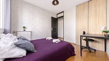 Een slaapkamer met een bed, een bureau en een kledingkast.