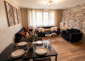 Un comedor con una mesa dispuesta para cuatro personas, un sofá y una lámpara.