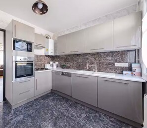 Una cocina moderna con horno empotrado, un lavamanos y un salpicadero de mármol.