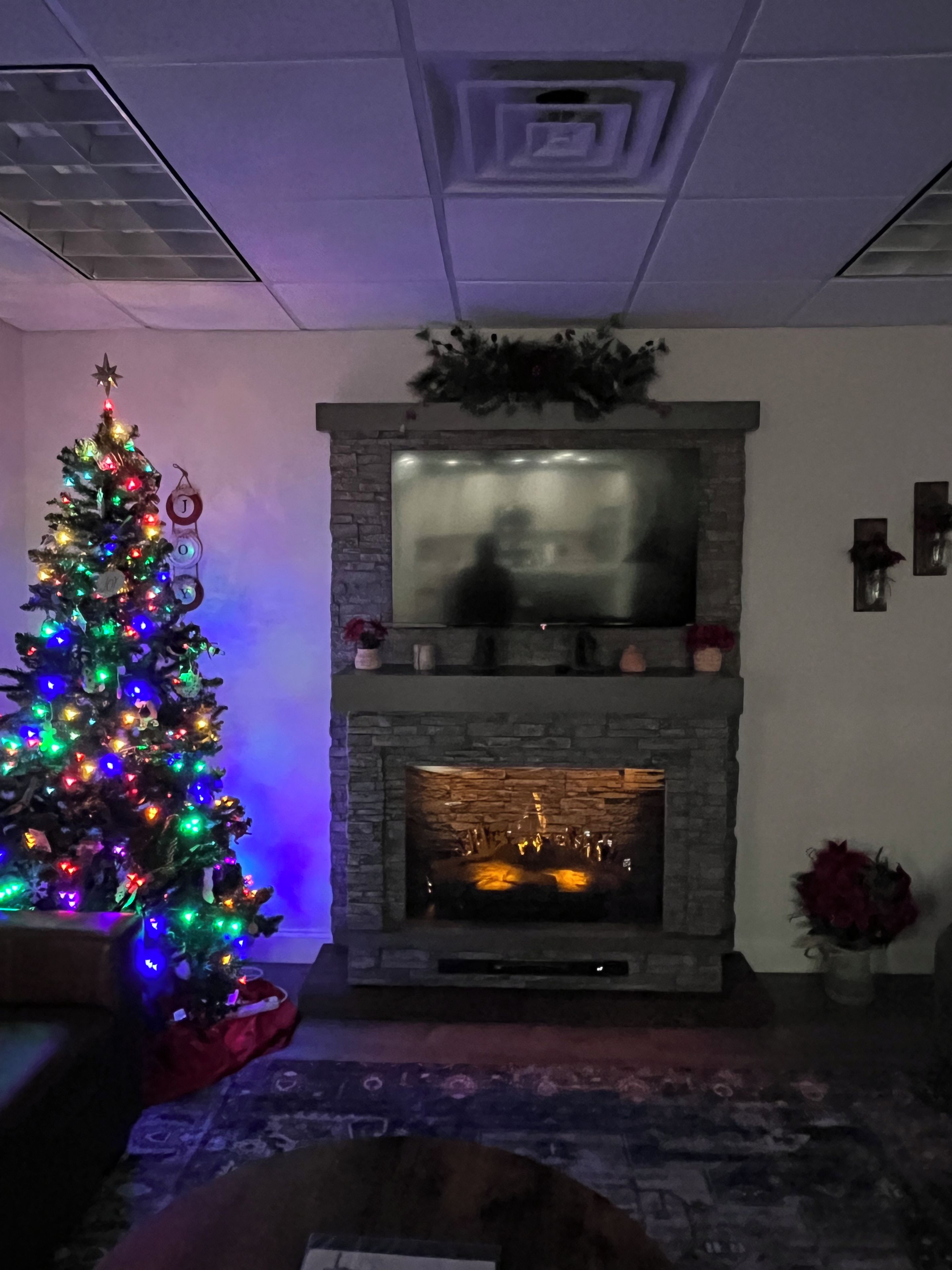 Una sala de estar con chimenea, árbol de Navidad y sofá.
