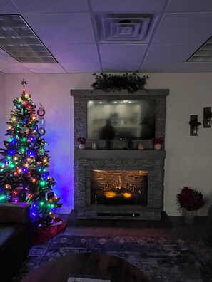 A living room with a fireplace, a Christmas tree, and a couch.