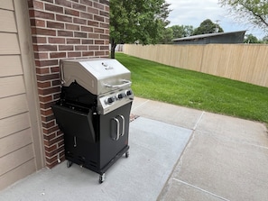 A portable gas grill with a digital display, a side burner, and a lid.
