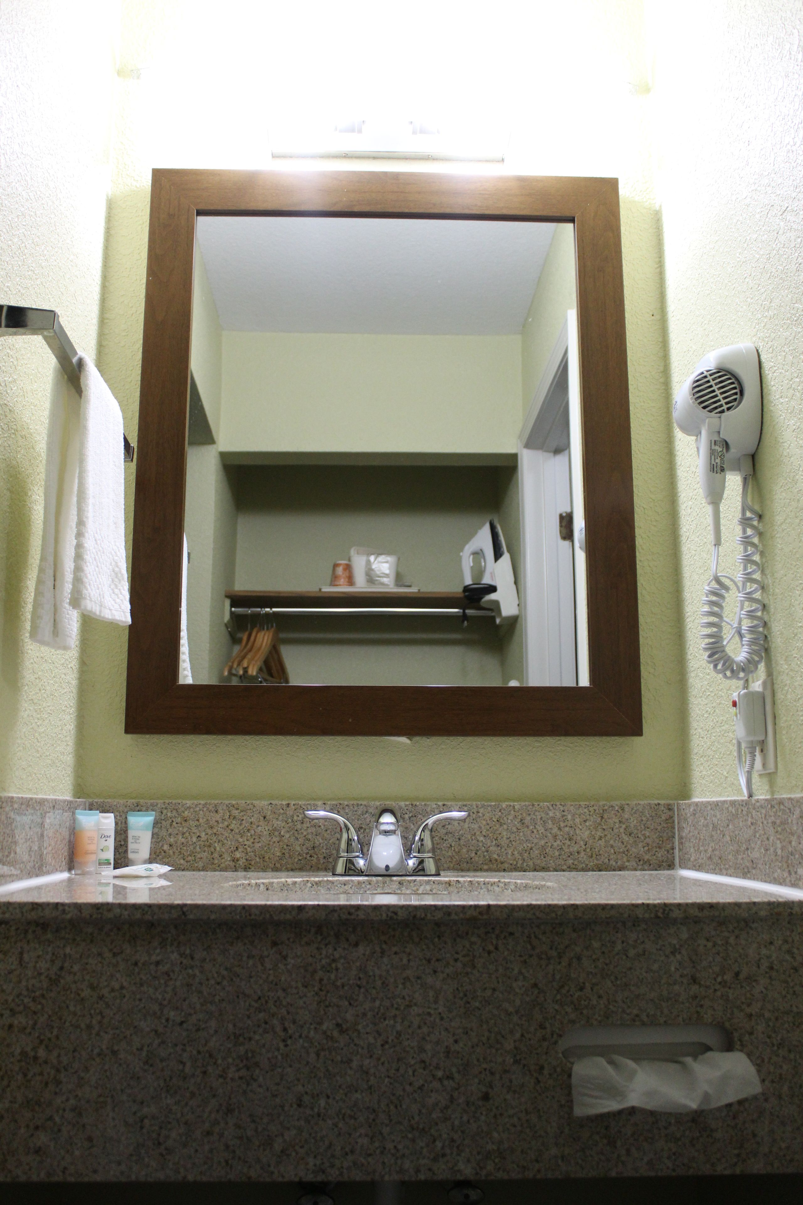 Un baño con lavamanos, espejo, toallero y secador de pelo.