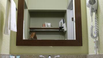 Un baño con lavamanos, espejo, toallero y secador de pelo.