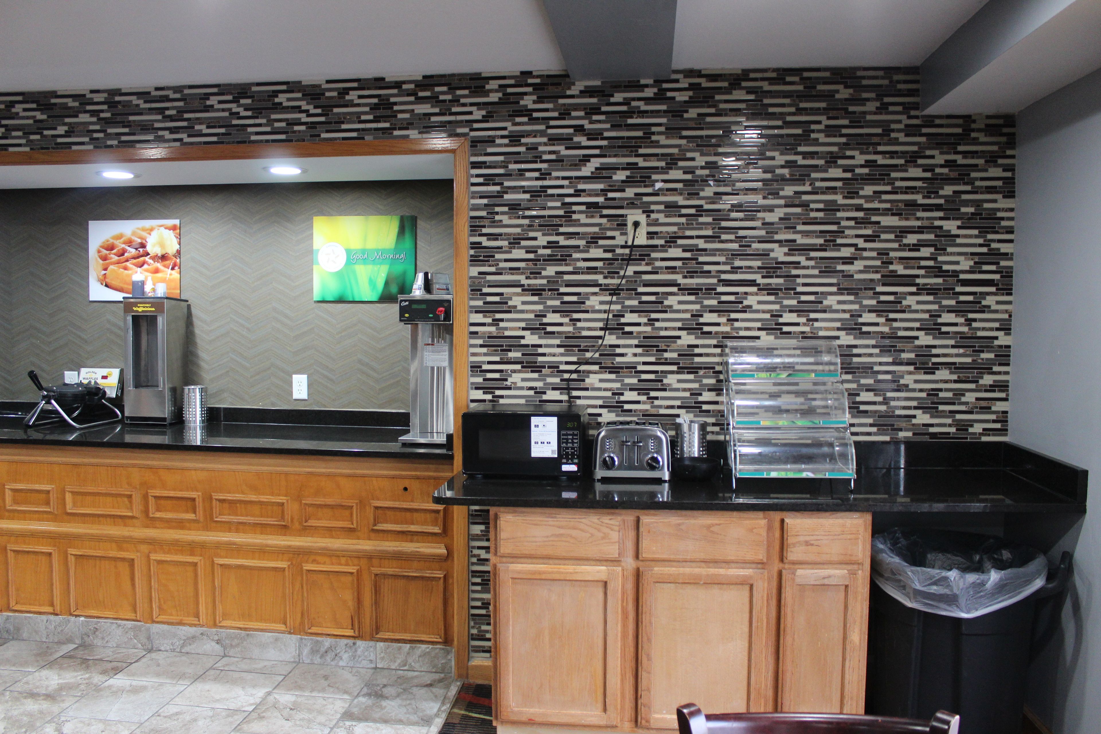 A kitchen area with a coffee machine, toaster, and waffle maker on the counter.