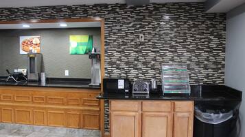 A kitchen area with a coffee machine, toaster, and waffle maker on the counter.
