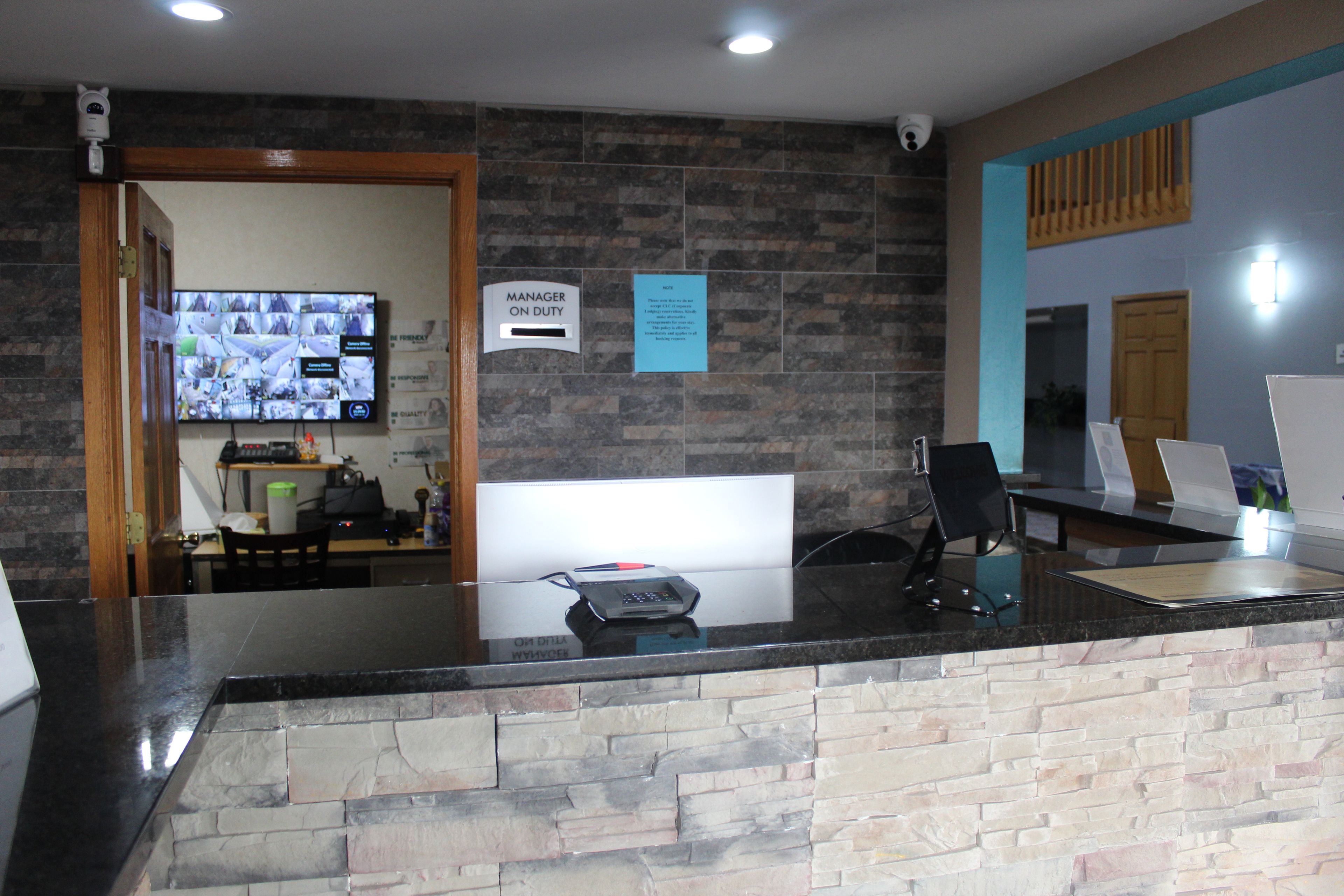 A reception desk with a stone wall, a digital display, and a sign indicating the manager is on duty.