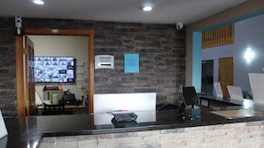 Mostrador de recepción con pared de piedra, pantalla digital y aviso indicando que el gerente está de servicio.