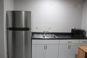 Una cocina con un refrigerador de acero inoxidable, un lavamanos doble y un microondas.
